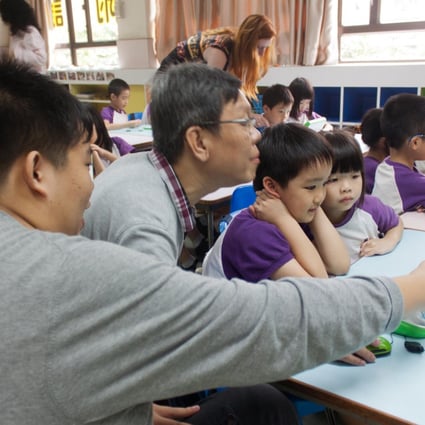 Kelvin Yu (left) and Kang Tsz-kit show Tin Shui Wai kindergarten students how to use the XO laptops.Photos: Alan Wong