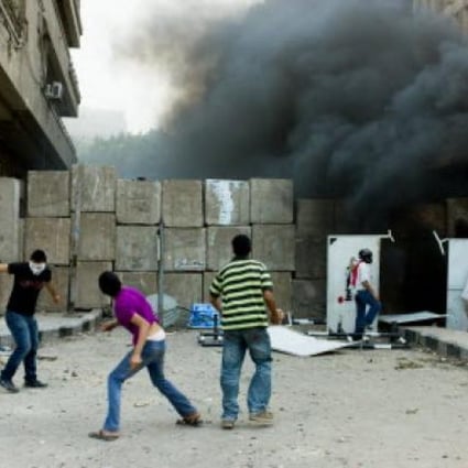 Protesters throw stones over a wall set outside the US embassy in Cairo in Egypt. Photo: Xinhua