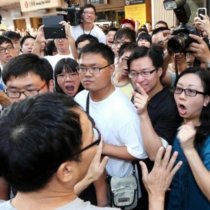 A supporter of the cross-border traders tries to placate angry local protesters outside Sheung Shui station yesterday. Photo: David Wong