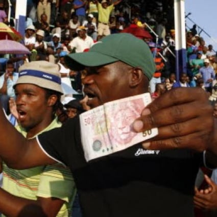 Miners sing and dance while holding South African bank notes in Lonmin Platinum Mine on Tuesday. Striking miners have accepted an offer of a  22 per cent pay increase to end more than five weeks of industrial action. Photo: AP
