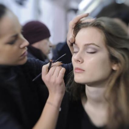 A make-up artist applies the barely there smoky-eye look backstage at Valentino's autumn-winter fashion show.