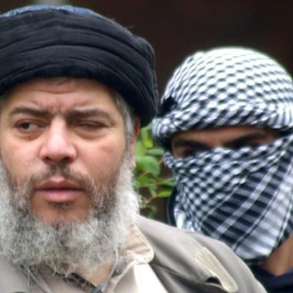 Muslim cleric Abu Hamza al-Masri flanked by a masked bodyguard. Photo: AP