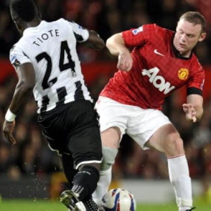 Manchester United's Wayne Rooney (right) is tackled by Newcastle's United's Cheick Tiote (left) during their English League Cup third round match at Old Trafford in Manchester, England on Wednesday. Photo: Associated Press 