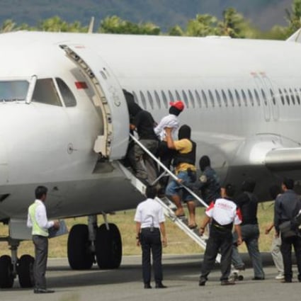 Terror suspects are escorted into a plane at Mutiara airport by anti-terror police in Palu, Sulawesi, on Wednesday. Photo: AFP
