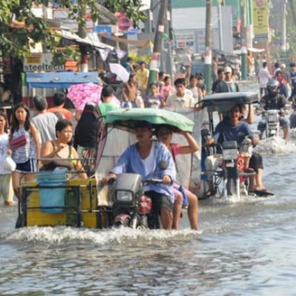 Residents commute along a flooded stretch of road in Calumpit town, north of Manila on August 11. Photo: AFP