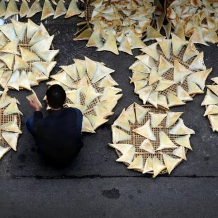 A worker lays shark fins on mats to dry outside a seafood store in Western District. Photo: Sam Tsang