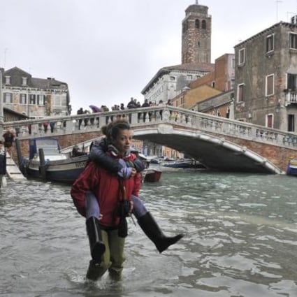 People walk in high water near the Ponte delle Guglie in Venice, Italy. Joseph Stiglitz says global warming is one of the long-term problems our world is facing. Photo: AP 