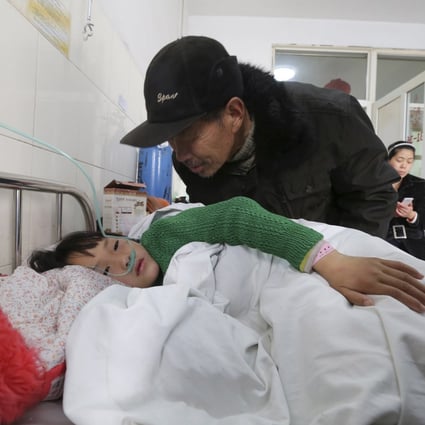 An elderly man talks to a girl who was injured after a stampede accident at a primary school, at a hospital in Xiangyang, Hubei province. Photo: Reuters