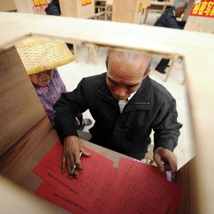 A woman watches her husband fill out his ballot paper in the remote Guangdong fishing village of Wukan in March last year. Photo: AFP