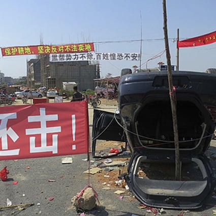 A red sign reading "We must retaliate" is next to an upended car at the entrance of Shangpu village in Guangdong province last week. Photo: Reuters