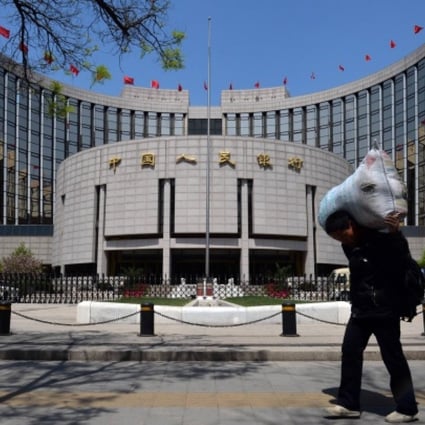 A Chinese migrant worker passes by The People's Bank of China as he heads to a bus station in Beijing. Photo: AFP