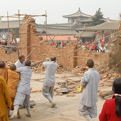 Monks pull down a wall built by a developer in front of Famen Temple, in protest against rapid commercialisation in 2009. Photo: SCMP Pictures