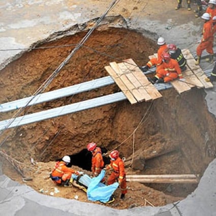 Rescuers prepare to move a dead body found in a sinkhole on a road in Shenzhen, south China's Guangdong province, on Tuesday. Photo: AFP