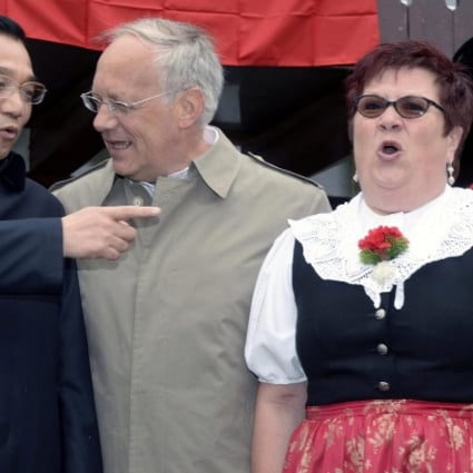 Li Keqiang comments to Swiss minister Johann Schneider-Ammann as yodellers perform. Photo: EPA