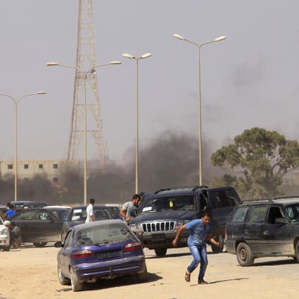 Protesters take cover during an attack on a Libyan militia headquarters in Benghazi. Photo: Reuters