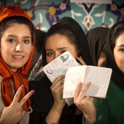 Iranian voters display their identity cards before casting their ballots at a polling station in northern Tehran. Photo: Xinhua