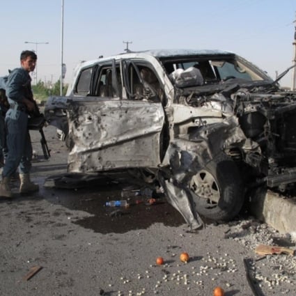 Afghan policemen gather around a damaged armed vehicle at the site of the suicide car bombing in Helmand province, Afghanistan. Photo: Xinhua