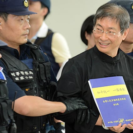 Chang An-lo displays a document that reads "On China Two System" as he is escorted away by police after landing at the Songshan Airport. Photo: AFP