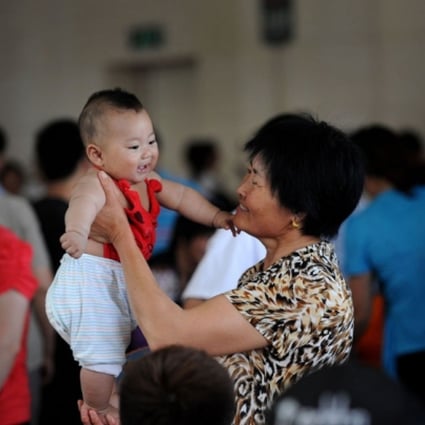 A Chinese granny holding a baby up.