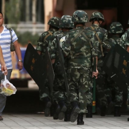 Residents walk past armed police in Kashgar. Photo: Reuters