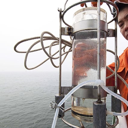 A scientist takes a water sample in north China's Bohai Bai, in July 2011, near two oilfield platforms that were estimated to have leaked 240 cubic metres of oil in June 2011. Photo: Xinhua
