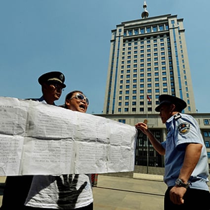Police detain a demonstrator who was protesting against the Chinese justice system on Wednesday outside the Intermediate People's Court in Jinan, Shandong province where disgraced politician Bo Xilai will soon go on trial. Photo: AFP 