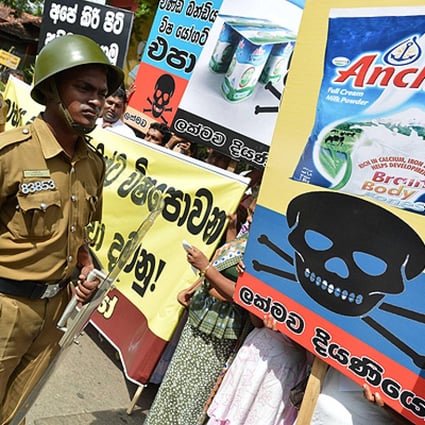 Police officers stand guard as local activists protest against alleged contaminated products in front of a Fonterra factory in Colombo. Photo: Xinhua
