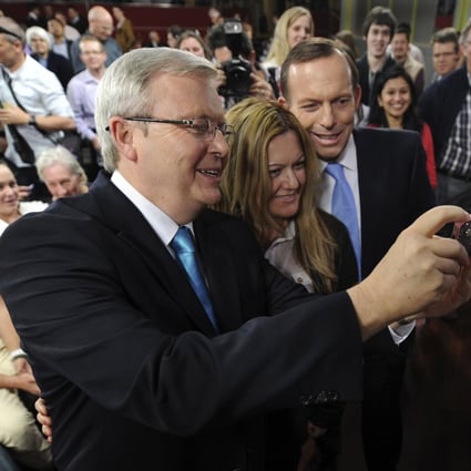 A  member of the public poses for a picture taken by Australian Prime Minister Kevin Rudd (left) next to opposition leader Tony Abbott. Photo: Reuters