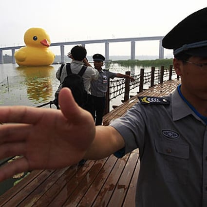 Security guards try to prevent photographers taking pictures of the inflated rubber duck created by Dutch artist Florentijn Hofman in Beijing on Sunday. Photo: Reuters