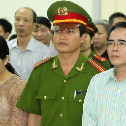 Lawyer Le Quoc Quan (right) and accountant Pham Thi Phuong stand with a policeman during their trail at a court in Hanoi. Photo: Reuters