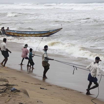 Fishermen pull a boat from the waters of the Bay of Bengal to safer ground at Podampata. Photo: Reuters