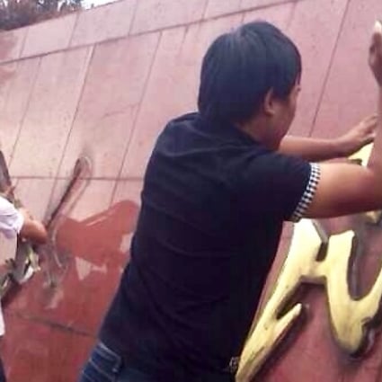 Yuyao residents take down the "Serve the People" logo outside their municipal government compound on Tuesday. Screenshot via Sina Weibo