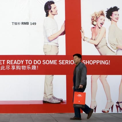 A shopper walks past a billboard for an upcoming H&M store in Beijing. Photo: Bloomberg