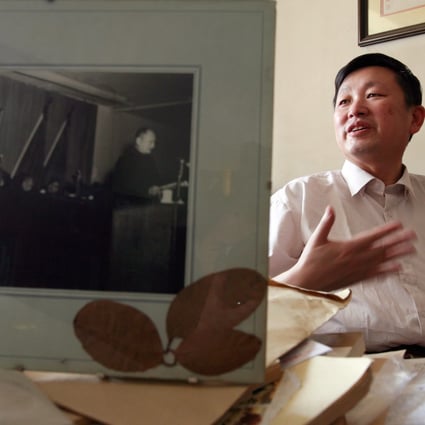 Zhang Lifan speaks behind a photograph featuring his father Zhang Naiqi (right) speaks while late Communist leader Mao Zedong (left) listens during an interview at his office in Beijing. Photo: AFP