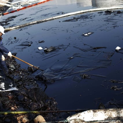 Worker cleans up leaked oil after last week's explosion of a Sinopec Corp oil pipeline in Huangdao. Photo: Reuters
