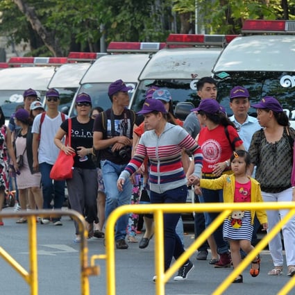 Foreign tourists walk past police vans outside the parliament building in Bangkok on Tuesday. Photo: AFP