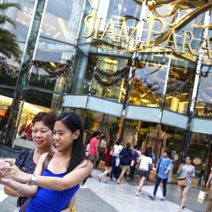 People take selfies in front of the Siam Paragon in Bangkok. Photo: Reuters