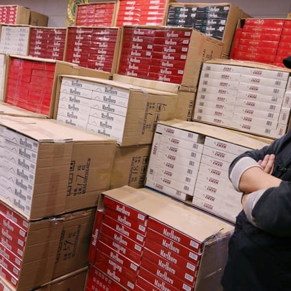 A customs officer at the department's headquarters guards about HK$10 million worth of illegal cigarettes seized during a raid last month. Photo: David Wong