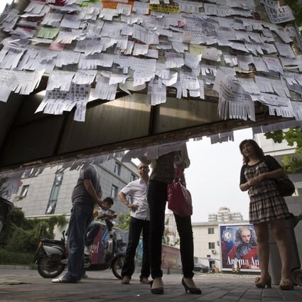 Pedestrians on a Beijing street check out adverts for rented rooms, flats or houses. Photo: Andy Wong