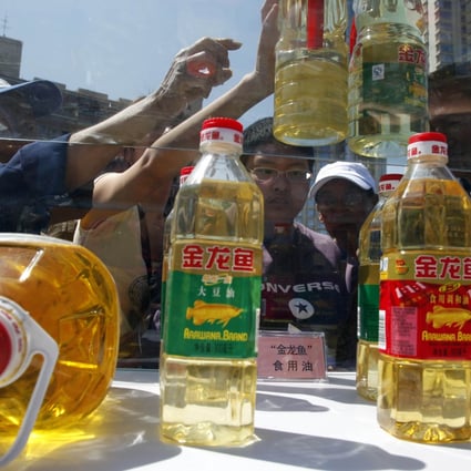 Beijing residents try to tell counterfeit cooking oil products from the real thing during an event to promote awareness of economic crimes. Photo: AP 