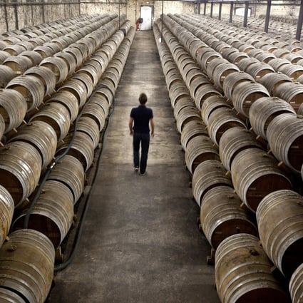 An employee walks between barrels of Remy Martin Fine Champagne Cognac, laid to age in a cellar at the Remy Cointreau SA headquarters in Cognac, France.