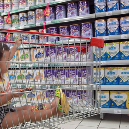A baby watches as his mother selects milk powder in a supermarket in Haikou, Hainan province. Photo: AFP
