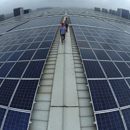 Workers walk between solar panels on the roof of Hangzhou East railway station in Zhejiang province. Photo: AP