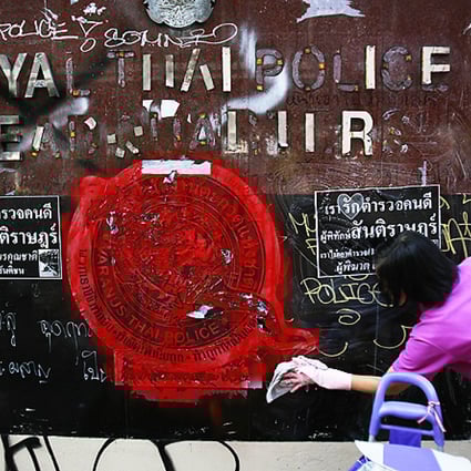 An anti-government protester volunteers to clean graffiti debris from the main gate of the Royal Thai Police Headquarters in Bangkok on Saturday. Photo: Reuters