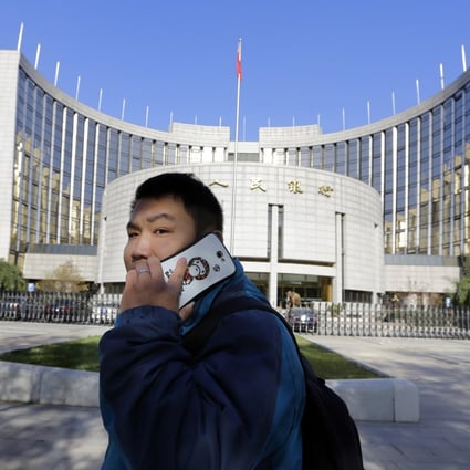 A man uses his mobile phone while walking past the headquarters of the People's Bank of China (PBOC), the central bank, in Beijing. Photo: Reuters