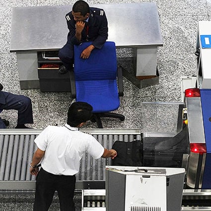 Airport security personnel chat as a pilot has his bag screened at the departure hall of the Kuala Lumpur International Airport in Sepang. Photo: Reuters
