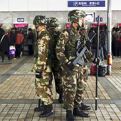 Armed paramilitary policemen stand guard next to ticket booths after at Kunming railway station. Photo: Reuters