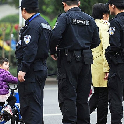 A young cyclist stares at police as they stand guard yesterday outside Xianning court, where mining tycoon Liu Han went on trial. Photo: AFP
