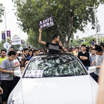 A man raises a placard which reads "Oppose PX (paraxylene petrochemicals), give me back my pure land", as he and other residents protest against a chemical plant project in Maoming, Guangdong province. Photo: Reuters