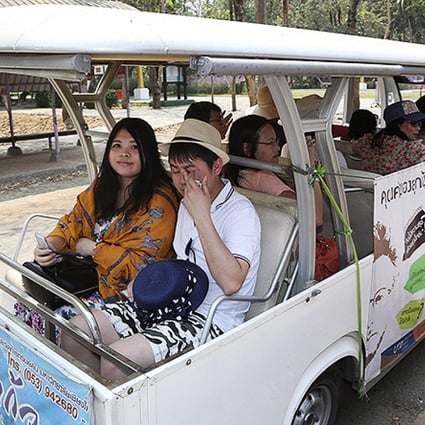 Chinese tourists ride on a cart while touring Chiang Mai University. Photo: AP